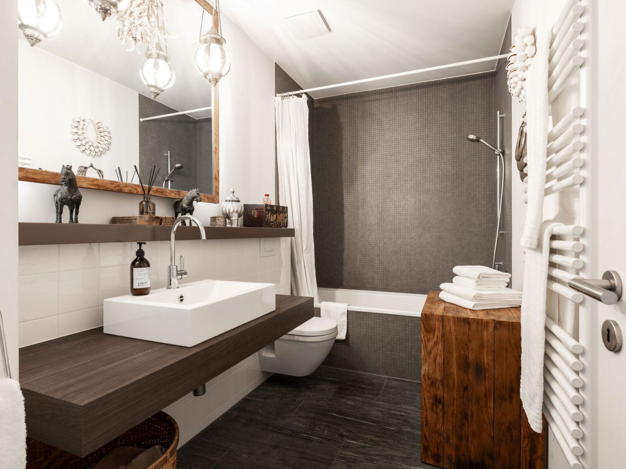 Ein modernes Badezimmer mit großem Spiegel, Waschbecken, Toilette und Duschbereich.
