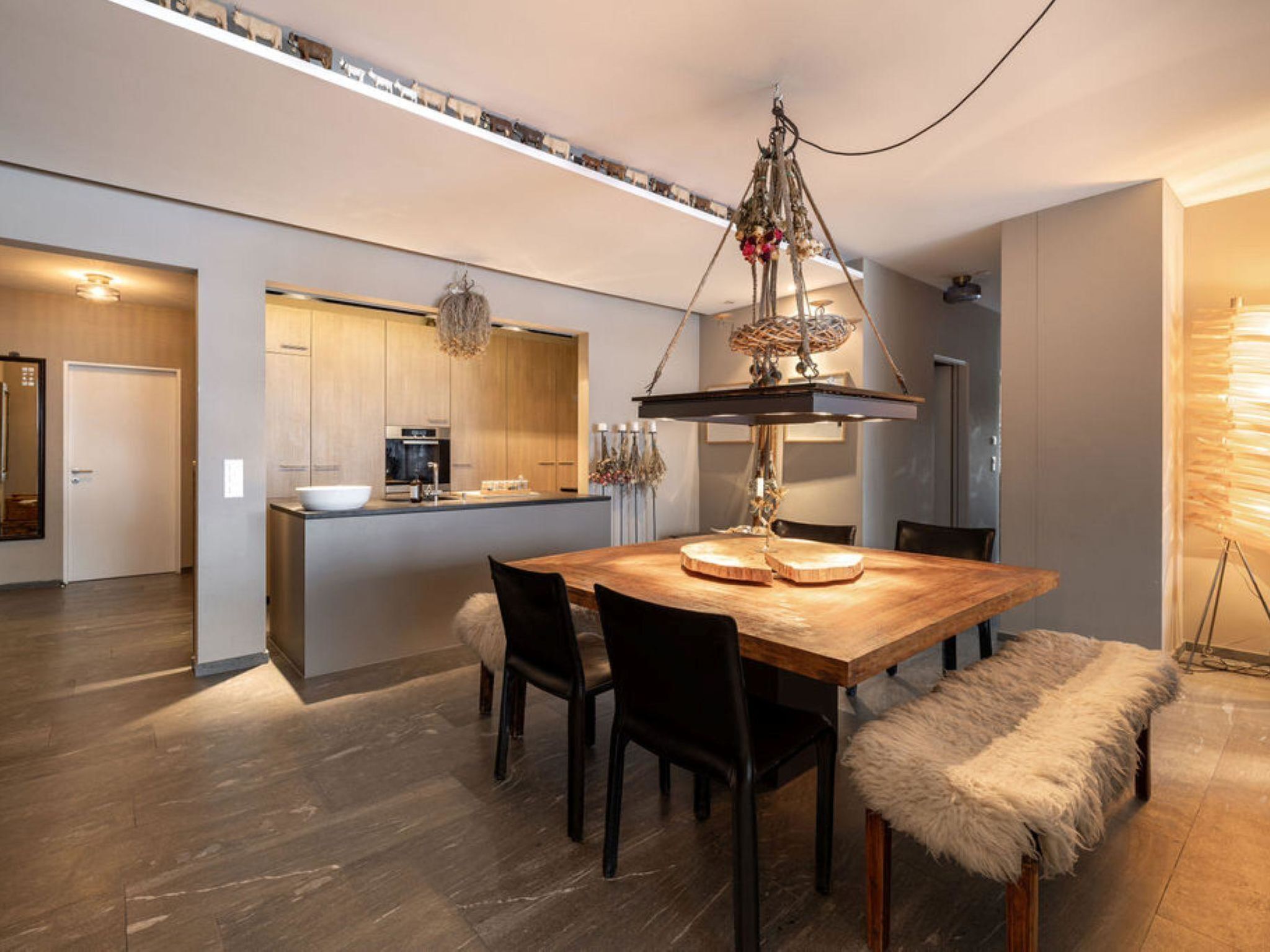 A modern kitchen with wooden cabinets, a central island, and a hanging light fixture.