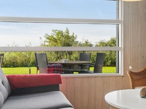 A room with a large window, a sofa, a small table, and two chairs.