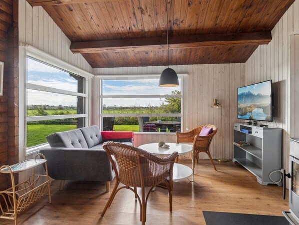 A cozy living area with a sofa, chairs, a table, and a TV.