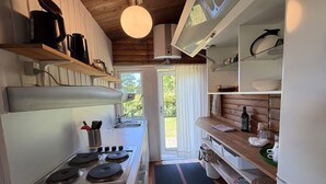 A compact kitchen with a stove, sink, and wooden shelves. - "Vilmar" - 450m from the sea by Interhome (Nykøbing Sj)