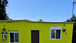 A small, single-story building with a bright yellow exterior, a central door, and two windows on either side.