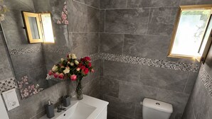 A bathroom with a white vanity, a toilet, and a window.