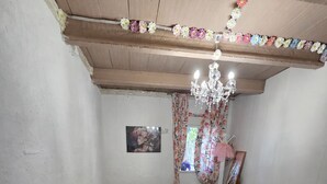 A bedroom with a bed, a wooden chest, a mirror, and a chandelier.