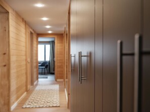 A hallway with wooden walls, a patterned rug, and a door with a handle. - Grabahus Appartement/Fewo, Dusche oder Bad, WC, 9-Bettwohnung by Interhome (Arosa)