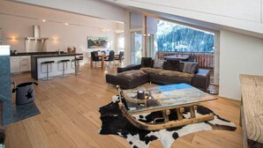 A modern interior with a kitchen, dining area, and a cozy living space with a large window overlooking a snowy landscape. - Juggasunna Appartement/Fewo, Dusche und Bad, WC, 7-Bettwohnung by Interhome (Arosa)