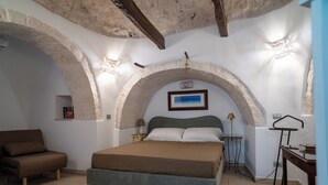 Un dormitorio con cama, sofá, una mesita y una lámpara.