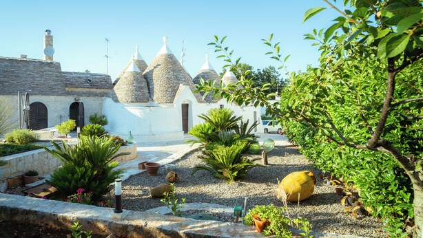 Un patio con edificios de piedra, plantas en macetas y un objeto amarillo grande.