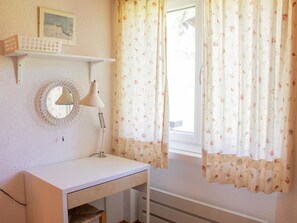 A room with a white desk, a wall-mounted lamp, a framed picture, and floral curtains. - Haus Christina Dohlengiebel Appartement/Fewo, Dusche und Bad, WC, 3 Schlafräume by Interhome (Arosa)