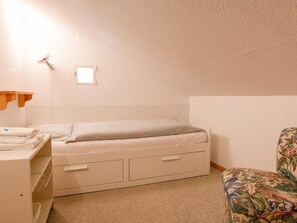 A small, single-bed room with a wooden desk, a chair, and a small window. - Haus Christina Dohlengiebel Appartement/Fewo, Dusche und Bad, WC, 3 Schlafräume by Interhome (Arosa)