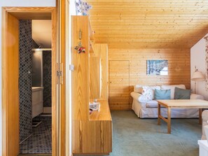 Una habitación acogedora con techo de madera, un sofá, una mesa y un armario de madera.