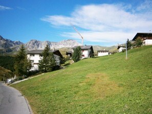 Una zona residencial con casas en una colina, una carretera y una montaña al fondo.