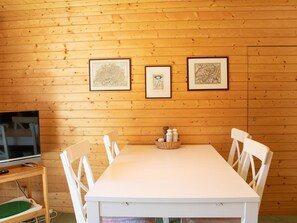 A wooden-paneled room with a dining table, chairs, a television, and framed artwork on the wall. - Haus Christina Dohlengiebel Appartement/Fewo, Dusche und Bad, WC, 3 Schlafräume by Interhome (Arosa)
