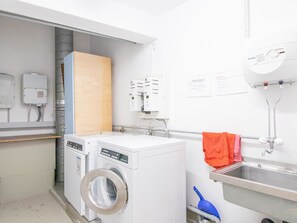 A laundry room with two front-loading washing machines, a utility sink, and a water heater. - Viktoria B32 by Arosa Holiday Appartement/Fewo, Bad, WC Viktoria 32 by Interhome (Arosa)