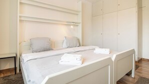 Un dormitorio con cama, dos almohadas, una mesita de noche y un armario.