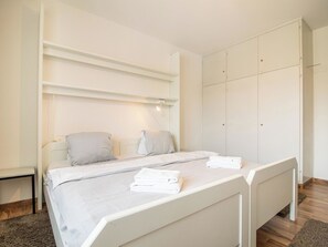 A bedroom with a bed, two pillows, a bedside table, and a wardrobe. - Viktoria B32 by Arosa Holiday Appartement/Fewo, Bad, WC Viktoria 32 by Interhome (Arosa)