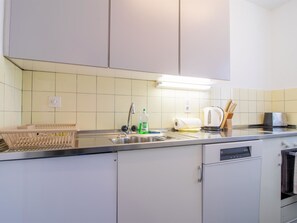 A kitchen with a stainless steel sink, a dish rack, a kettle, and a coffee maker. - Viktoria B32 by Arosa Holiday Appartement/Fewo, Bad, WC Viktoria 32 by Interhome (Arosa)