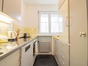 Eine kompakte Küche mit Einbauofen, Wasserkocher und Fenster über der Spüle.