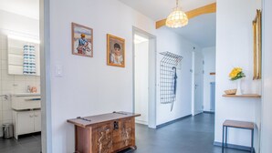 Un pasillo con un aparador de madera, una lámpara colgante y una puerta que da a otra habitación.