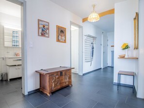 A hallway with a wooden cabinet, a hanging light fixture, and a door leading to another room. - Viktoria B32 by Arosa Holiday Appartement/Fewo, Bad, WC Viktoria 32 by Interhome (Arosa)