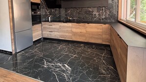 A modern kitchen with wooden cabinets, a black marble countertop, and a built-in oven. - M&R Riviera • Near the beaches • Air Conditioning • Terrace • Modern 5-bedroom apartment • 8 people (La Seyne-sur-Mer)