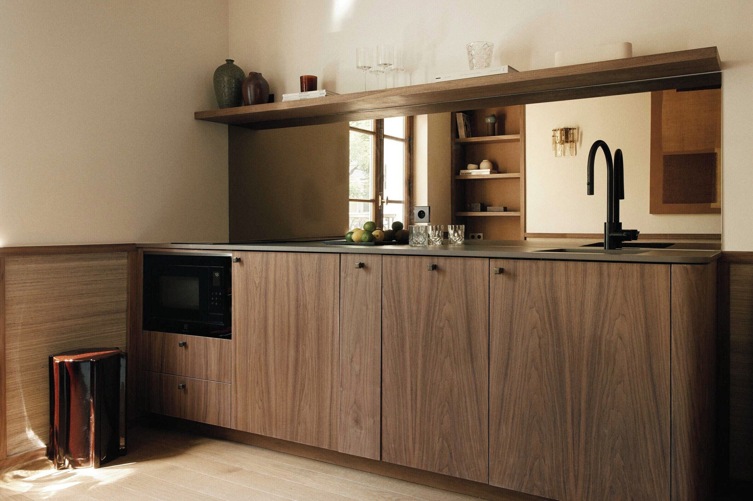 Una cocina con armarios de madera, microondas, pileta y ventana.