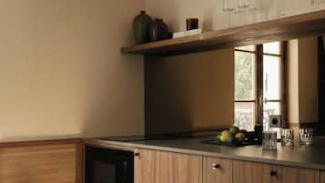 A kitchen with wooden cabinets, a microwave, and a small stool.