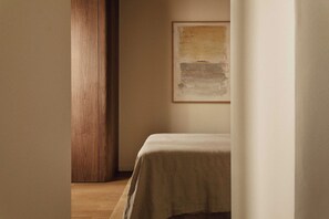 Una habitación con una cama, un pilar de madera y un cuadro en la pared.