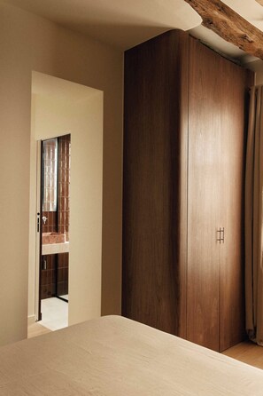 A bedroom with a large wardrobe, a bed, and a bathroom visible through an open door. - Cosy Apt A/C 1ch/4p - Montmartre / Place du Tertre (Paris)