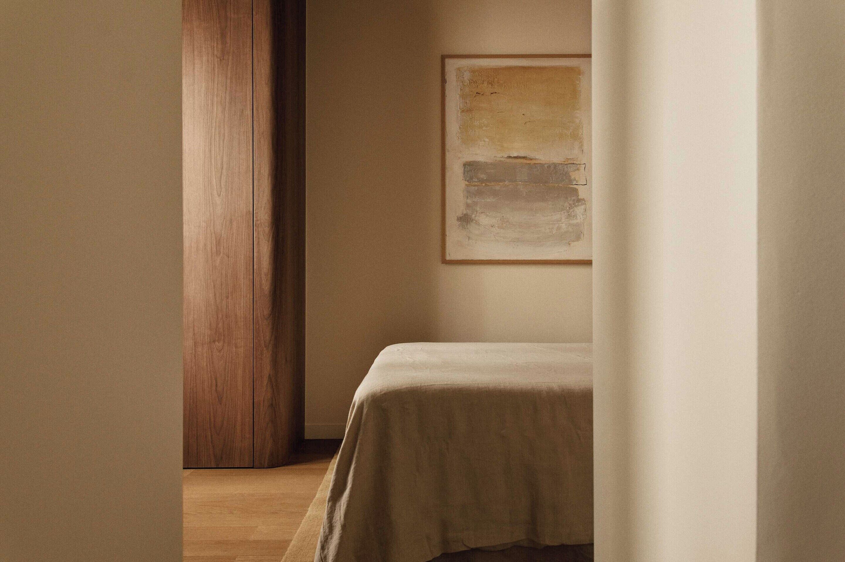 Una habitación con una cama, un pilar de madera y un cuadro en la pared.
