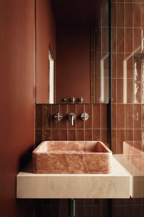 Un baño con un lavamanos rectangular, un espejo y una zona de ducha.