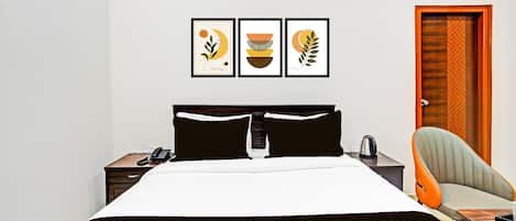 A hotel room with a bed, a nightstand with a phone, a chair, and a door.