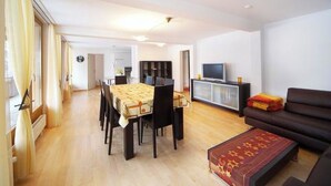 A spacious living area with a dining table, sofa, and television. - Luegisland Wohnung Salietti Appartement/Fewo, Dusche oder Bad, WC, 8-Bettwohnung by Interhome (Arosa)