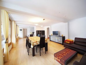 Ein geräumiger Wohnbereich mit Esstisch, Sofa und Fernseher.