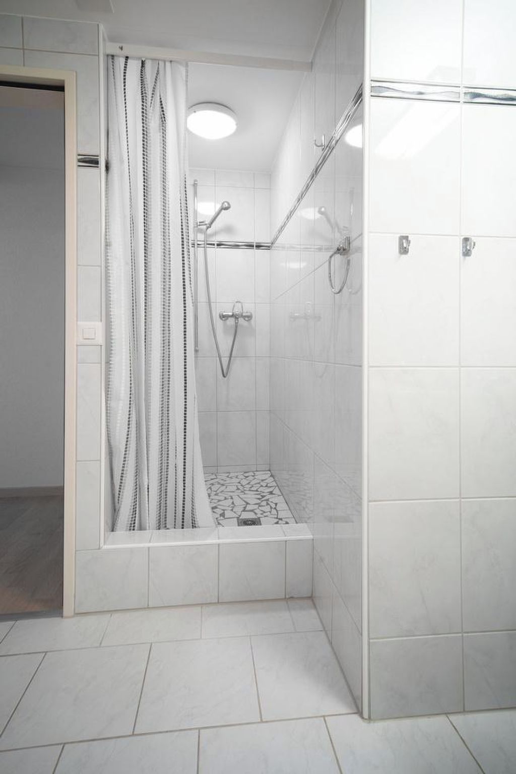 A shower with a glass door, a showerhead, and a tiled floor.