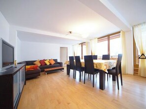 Ein Wohnzimmer mit einer Couch, einem Fernseher und einem Essbereich mit Stühlen und einem Tisch.