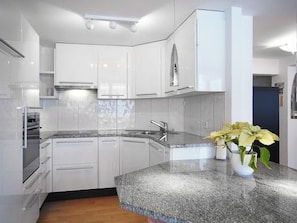Eine moderne Küche mit weißen Schränken, einer Granit-Arbeitsplatte und einer Edelstahl-Dunstabzugshaube.