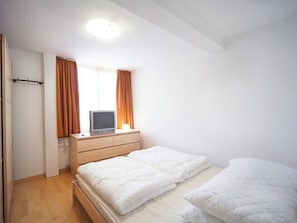 Ein Schlafzimmer mit einem Bett, einem Fernseher auf einer Kommode und einer Tür.
