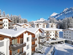 Une station de ski enneigée, composée de plusieurs bâtiments, de balcons et offrant une vue sur un paysage montagneux.