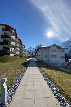 Un quartier résidentiel doté d’une promenade dallée, d’immeubles avec balcons et offrant une vue sur les montagnes.