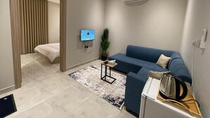 Una sala de estar moderna con un sofá, televisor, mesa de centro y un hervidor sobre una bandeja.