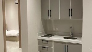 Una cocina moderna con armarios grises, encimera blanca y un lavamanos.