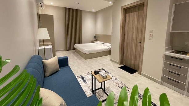 Una habitación de hotel moderna con un sofá azul, una cama, un escritorio y un armario.