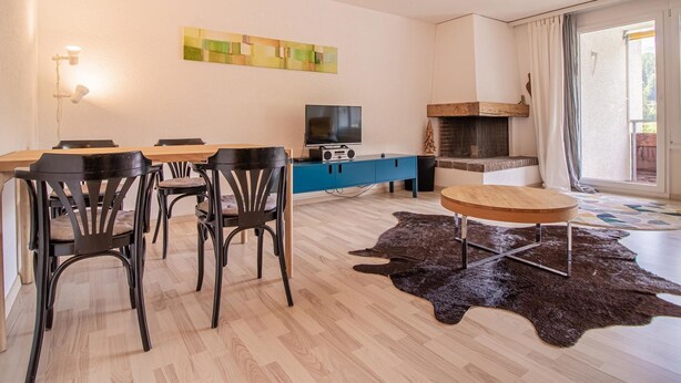 A modern living room with a dining area, a flat-screen TV, and a fireplace. - Rothornblick 63 by Arosa Holiday Appartement/Fewo, Dusche, WC Rothornblick 63 by Interhome (Arosa)