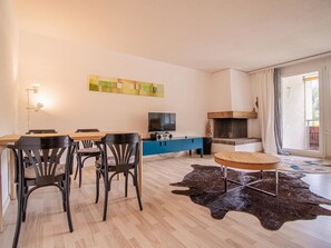 A modern living room with a dining area, a flat-screen TV, and a fireplace. - Rothornblick 63 by Arosa Holiday Appartement/Fewo, Dusche, WC Rothornblick 63 by Interhome (Arosa)