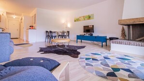 A modern living room with a sofa, a coffee table, a TV, and a fireplace. - Rothornblick 63 by Arosa Holiday Appartement/Fewo, Dusche, WC Rothornblick 63 by Interhome (Arosa)