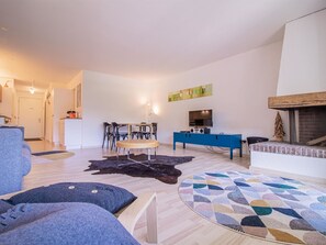 A modern living room with a sofa, a coffee table, a TV, and a fireplace. - Rothornblick 63 by Arosa Holiday Appartement/Fewo, Dusche, WC Rothornblick 63 by Interhome (Arosa)