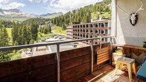 A balcony with a wooden floor, a table, and a chair. - Rothornblick 63 by Arosa Holiday Appartement/Fewo, Dusche, WC Rothornblick 63 by Interhome (Arosa)