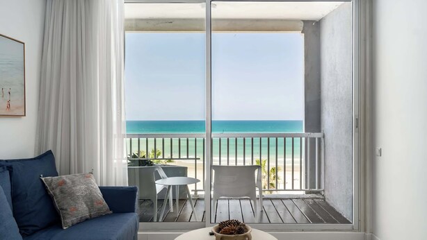 Un balcon avec vue sur la plage, un canapé, une table et une chaise.