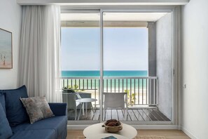 A balcony with a view of the beach, a sofa, a table, and a chair. - Modern 2BR Steps to Beach by HolyGuest (Tel Aviv-Yafo)